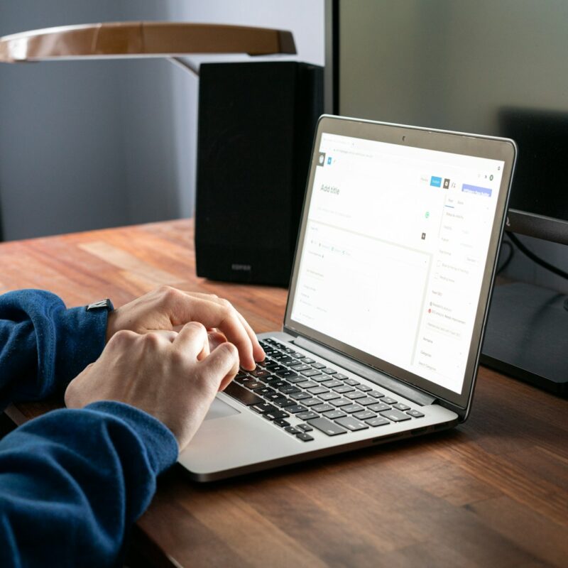 person using macbook pro on brown wooden table